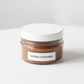 firm coffee lotion bar in a plastic round container with a white lid