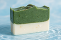 hademade soap with dark green half and creamy bottom with a light blue water background