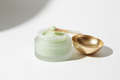light green face balm in a frosted glass with a gold open lid